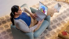 A woman sitting in a chair looking at a Windows 11 laptop